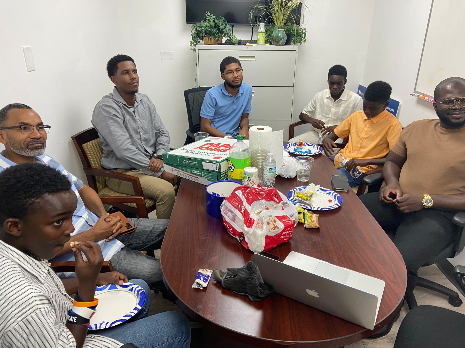 Young men and mentors seated around the conference table during the fireside